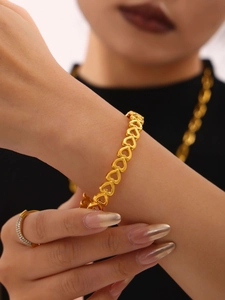 Detail shot of a 18K gold plated hollow heart link bracelet worn on a model wrist