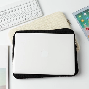 Close-up of quilted laptop sleeve in black and off-white with sleek metal zipper detail