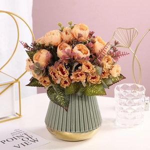 Artificial champagne peony bouquet in a green striped ceramic vase with gold base