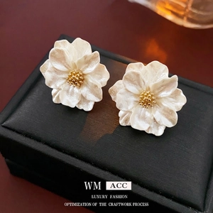 Minimalist resin flower earrings with gold center on textured black leather jewelry box