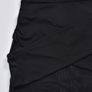 Detail shot of black mesh dress featuring ruched cross design and sheer fabric textures