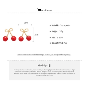 Detail view of resin cherry bow earrings with silver needles and size specifications