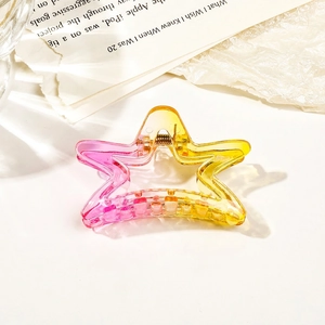 Macro detail of star-shaped hair claw clip in transparent pink and yellow gradient