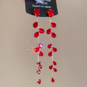 Detail shot of red teardrop crystals on long gold tassel earrings with vibrant sparkle