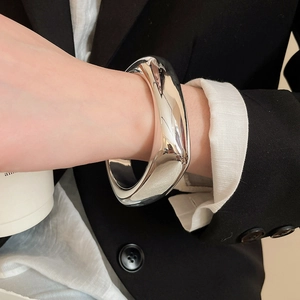 Macro shot of a chunky irregular silver cuff bracelet with a mirror-polished finish