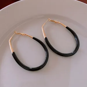 Boucles d'oreilles ovales rétro en émail noir et or sur une assiette en céramique