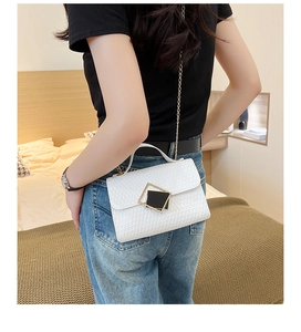 Detalle de bolso blanco con textura tejida, cadena dorada y cierre cuadrado geométrico