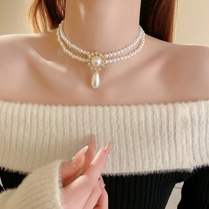 Close-up of double-layered pearl necklace with rhinestone flower and teardrop pendant