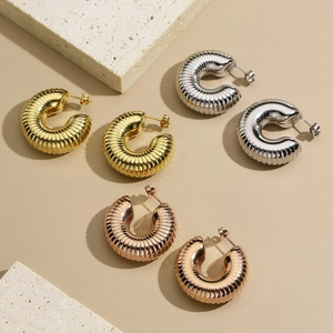 Detailed close-up of textured C-shape hoop earrings in gold, silver, and rose gold finish
