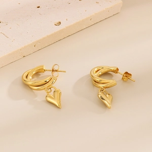 Detail of gold heart earrings with double hoops on a textured stone display