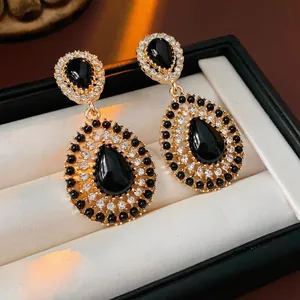 Vintage gold drop earrings with black stones and diamond accents in a jewelry box