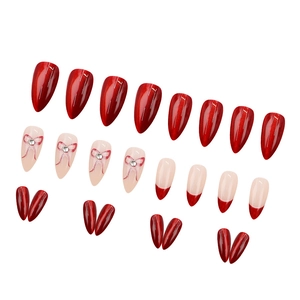 Deep red cat eye press-on nails with pink rhinestone bows and French almond tips