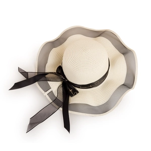 Detail of straw sun hat featuring a black ribbon bow with 'forever' print and lace trim