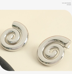 Détail macro de boucles d'oreilles spirales argentées avec finition métal polie