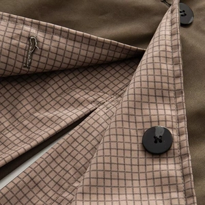 Close-up of brown faux fur trench coat collar with retro plaid lining and black button