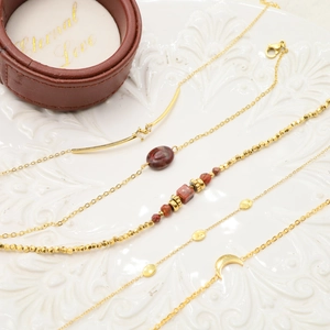 Detailed view of gold moon bracelets with natural stones on a white ceramic plate