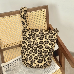 Detailed close-up of leopard print faux fur shoulder bag on a vintage wooden chair