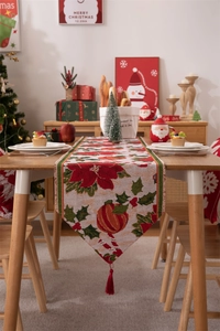 Dettaglio del runner da tavola natalizio con motivi festivi di stelle di Natale e nappe