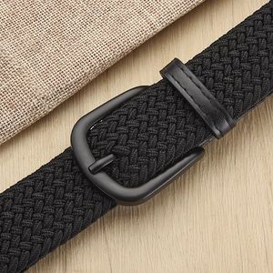 Elastic black woven stretch belt with metal buckle on a textured background