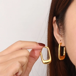 French style gold U-shaped chunky stainless steel hoop earrings worn by a model