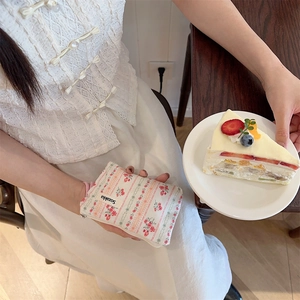 Close-up of beige floral cotton pouch with zipper and sozakka label held by a person
