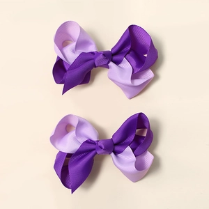 Detail view of double-layered ribbon bow hair clips in dark and light purple colors