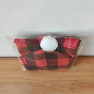 Détail de la housse de chaise de Noël à carreaux rouges et noirs avec pompon blanc