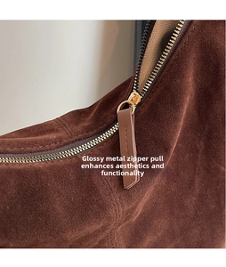Detail of dark brown suede bag featuring polished metal zipper and leather puller