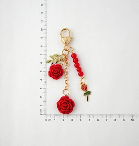 Detailed view of red resin rose keychain with gold leaf chain and scale measurement