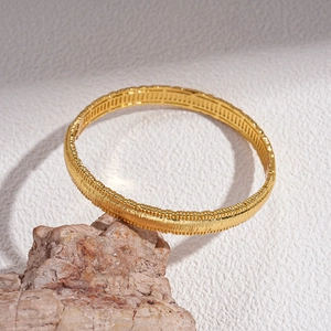 Detailed macro view of 18k gold plated bangle featuring vertical brushed metal textures