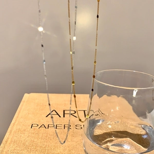 Détail artistique de colliers ras de cou dorés et argentés sur fond de livre épuré