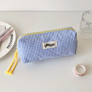 Detail of blue and white checkered quilted pencil case with yellow zipper and brand tag