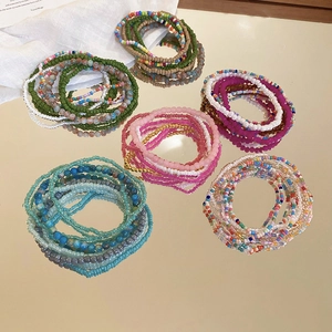 Detail of seven Bohemian beaded bracelets set in colorful layers on a mirror surface