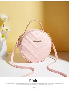 Close-up of pink round crossbody bag with V-quilted texture and gold hardware