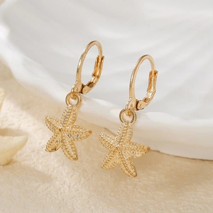 Detailed view of a textured gold starfish pendant on a soft sandy beach background