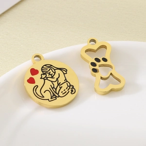 Detailed view of 18k gold pendants with dog paw and bone shapes on ceramic plate