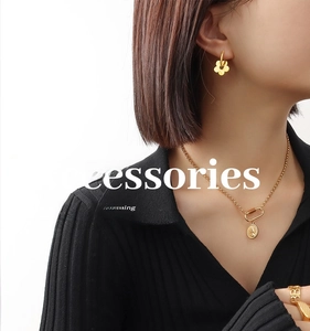 Detailed view of a model wearing a gold flower earring and coin pendant necklace set