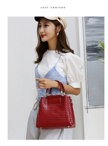 Detail of red woven texture handbag with golden hardware being held by a fashion model