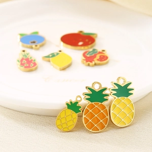 Macro shot of colorful enamel fruit pendants including pineapple and apple for DIY jewelry