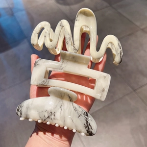 Detailed view of three large marble pattern hair claws in wave and rectangle shapes