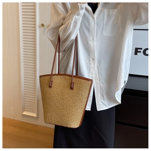Detail of woven straw tote bag with brown leather trim and handles for summer beach