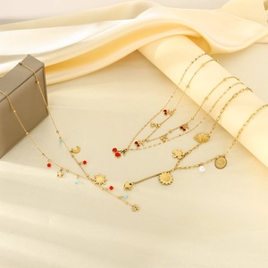 Detailed close-up of gold necklaces with cherry and sunflower charms on silk background
