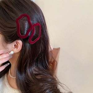 Detail showing two wine red flocked velvet wavy hair clips worn on deep brown curly hair