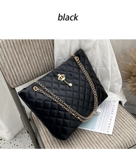 Detail of black quilted tote bag featuring golden chain straps and crown pearl charm