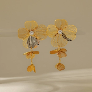 Detail of gold floral tassel earrings with hollow wire petals and white pearl centers