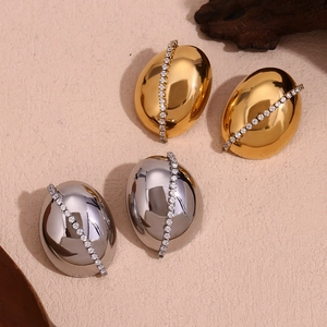 Macro view of oval gold and silver stud earrings with diagonal cubic zirconia inlay
