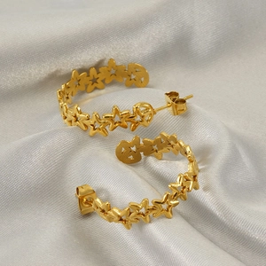 Polished gold stainless steel hoop earrings with hollow star patterns on silk background