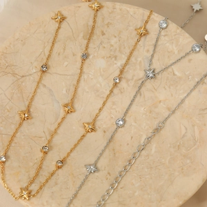 Colliers avec pendentif étoile polaire en acier doré et argenté sur plateau marbre