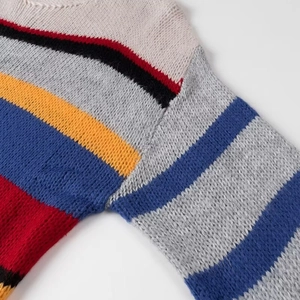 Close-up of rainbow striped knit sweater shoulder with beige, black, red and blue textures