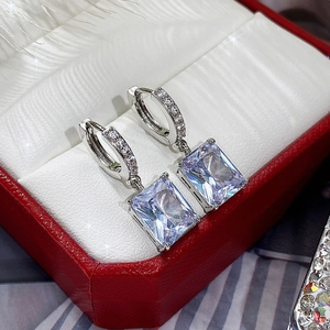 Detailed macro view of silver rectangle zircon drop earrings in a red jewelry box